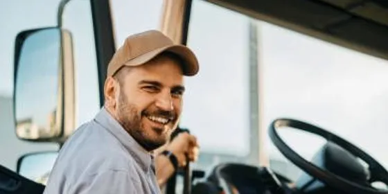 Caminhoneiro sorrindo, subindo na cabine do caminhão